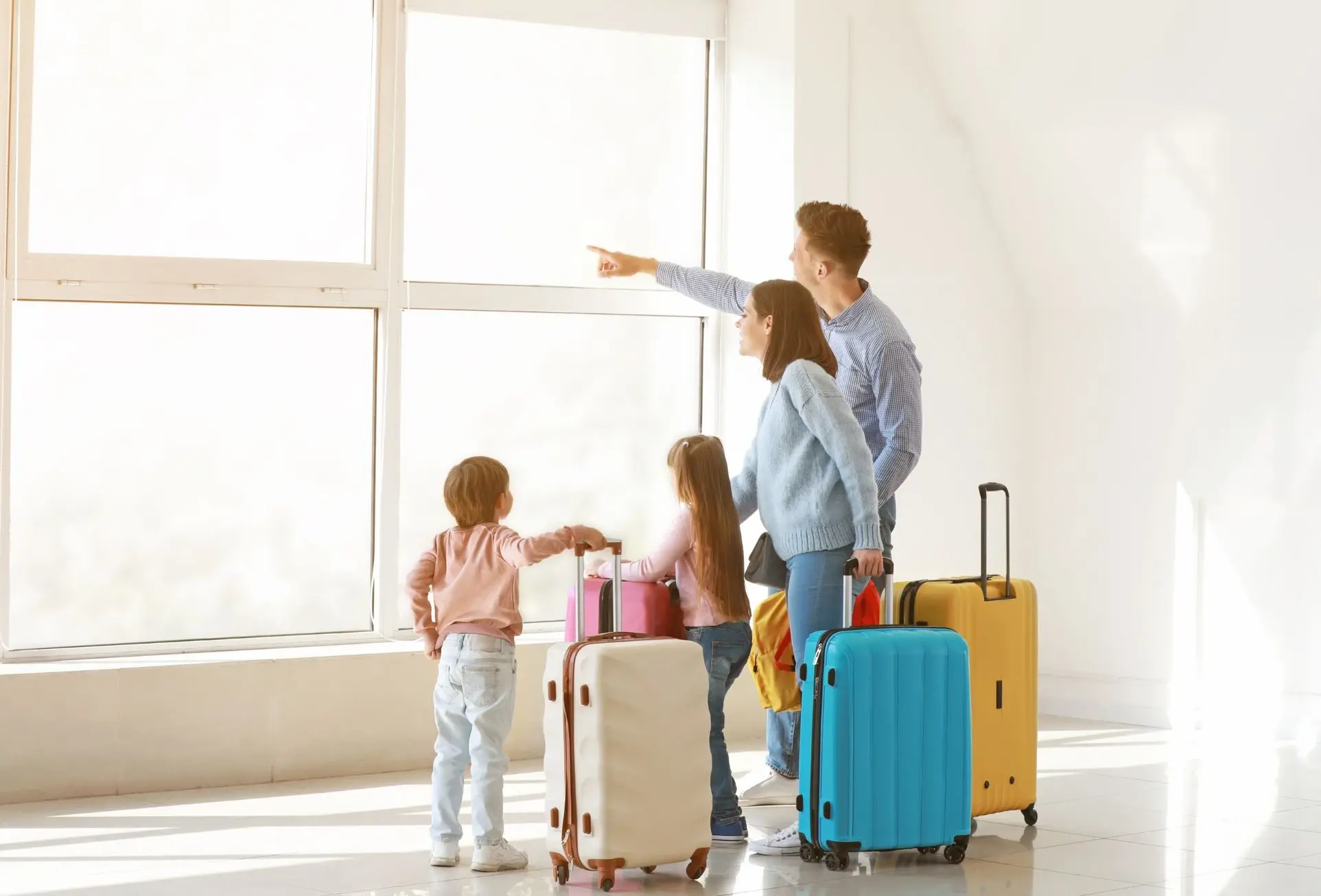 Familia con maletas en el aeropuerto observando por la ventana antes de su viaje.