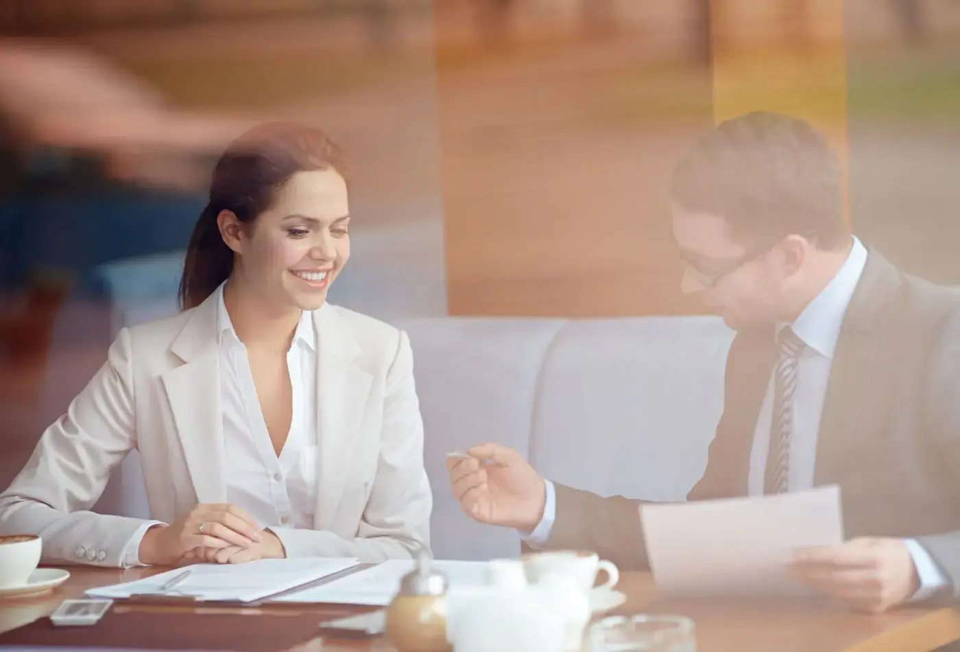 Mujer de negocios sonriendo mientras conversa con un colega durante una reunión en una cafetería.